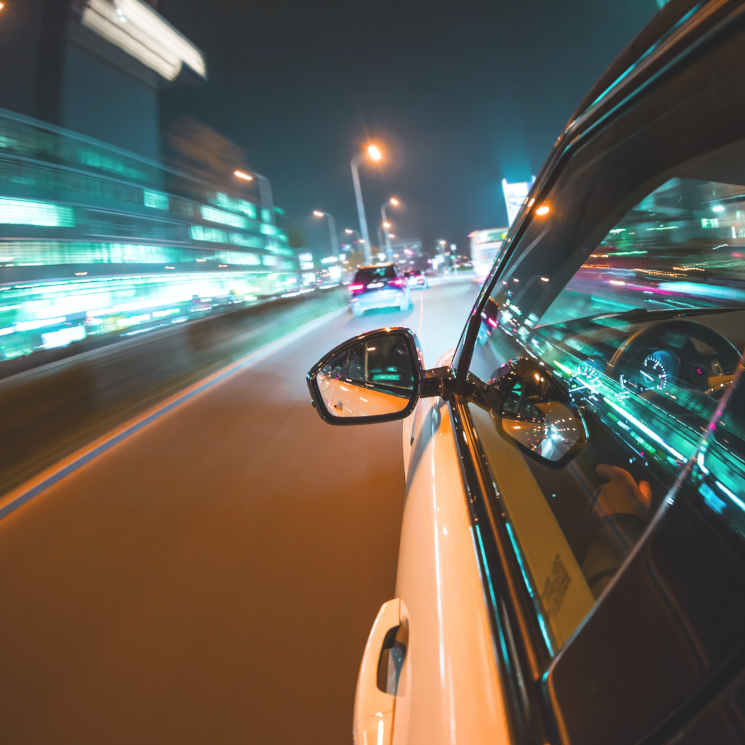 Side view of a car driving at night through a city street