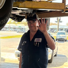 Orlando Fernandez, Transmission Rebuilder of AAMCO in South Tampa, under a lift in the shop garage, waving hello